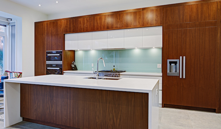 The Dunfield Kitchen design featuring a popular trend of mixing solid white and natural walnut. The client added a tempered glass backsplash that tie together the modern elements.